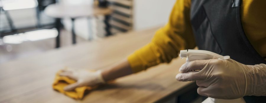 side-view-female-barista-cleaning-table-while-wearing-latex-gloves